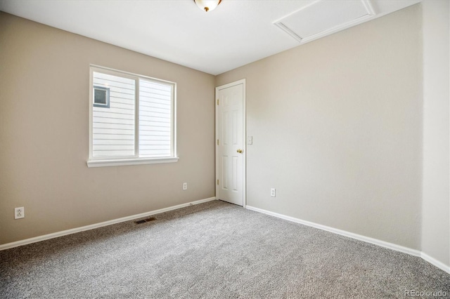 carpeted empty room with baseboards, visible vents, and attic access