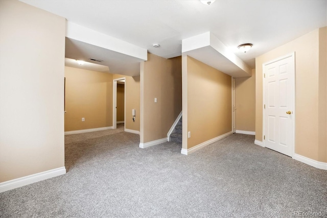 finished basement featuring visible vents, stairs, carpet floors, and baseboards
