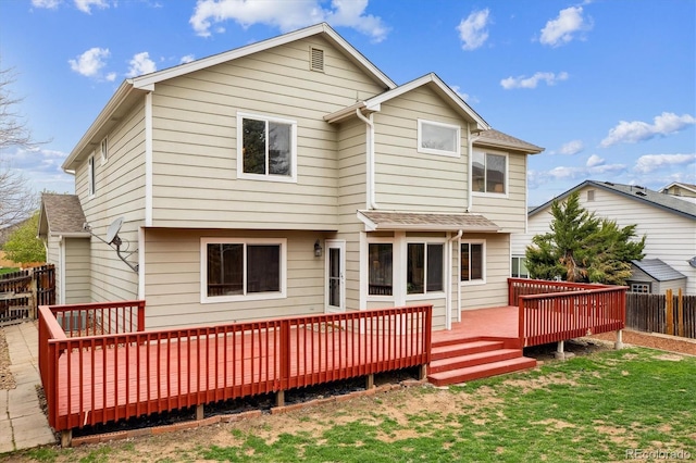 rear view of property with a yard, fence, a wooden deck, and a shingled roof