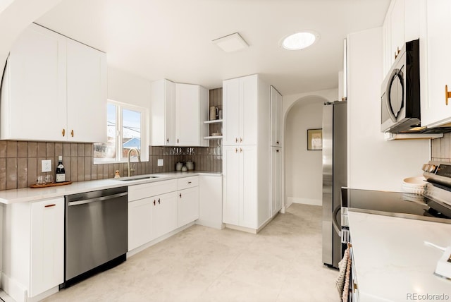 kitchen featuring sink, backsplash, stainless steel appliances, and white cabinets