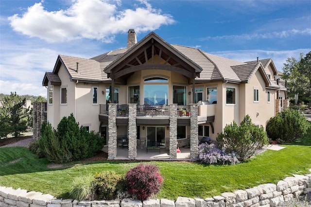 rear view of house featuring a balcony, a patio area, and a lawn