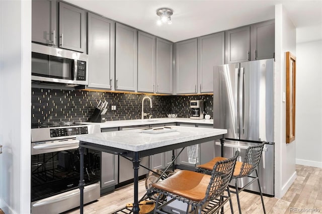 1200 Vine St Unit 5G, Denver, CO 80206 - kitchen with stainless steel appliances, gray cabinetry, light wood-style flooring, and tasteful backsplash