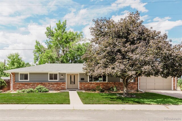 view of front of property featuring brick siding, concrete driveway, and a front lawn