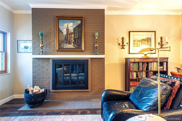 living area with ornamental molding, a brick fireplace, wood finished floors, and baseboards