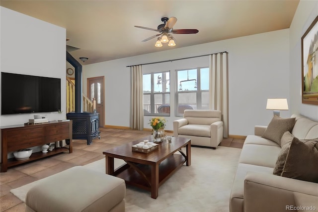 living room with ceiling fan, light tile patterned flooring, and a wood stove