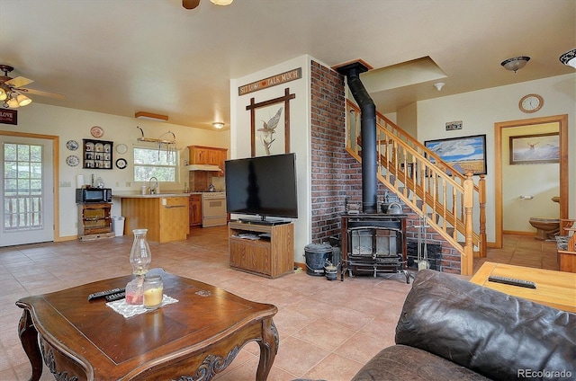 tiled living room featuring sink, ceiling fan, and a wood stove