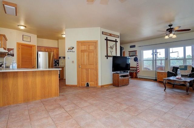 living room featuring ceiling fan, a baseboard radiator, and sink