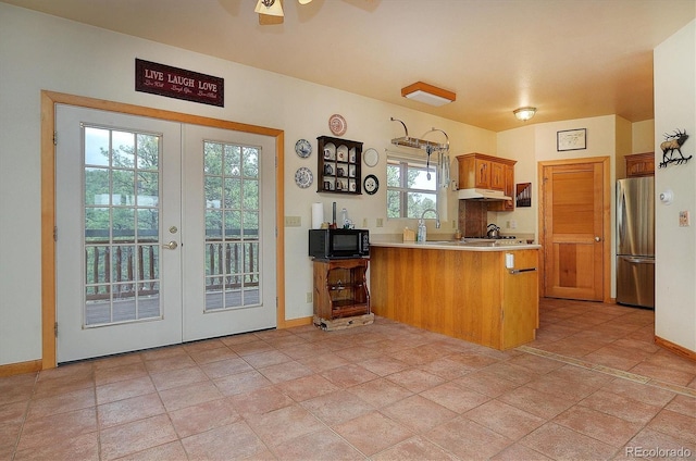 kitchen with stainless steel refrigerator, kitchen peninsula, ceiling fan, french doors, and sink