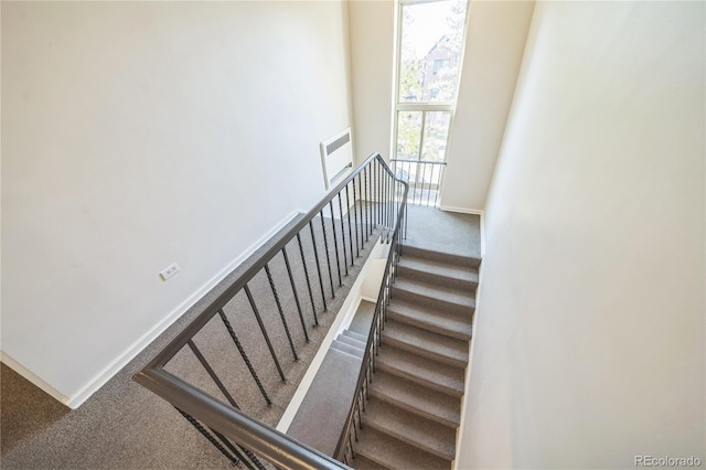 stairs with baseboards, carpet floors, and a towering ceiling