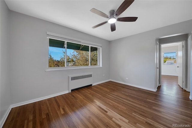 empty room with ceiling fan, radiator heating unit, baseboards, and wood finished floors