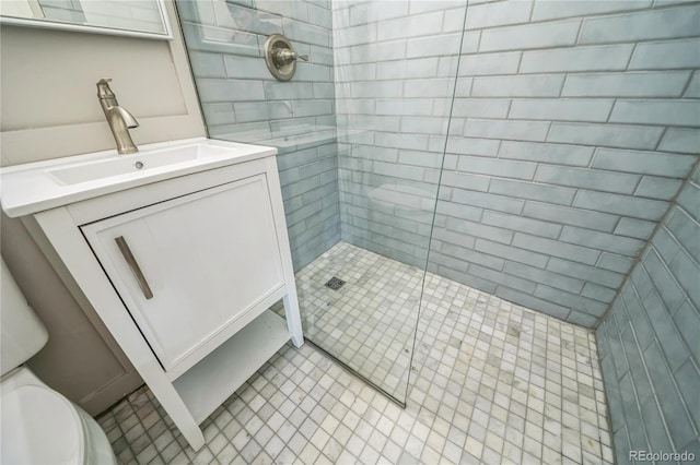 bathroom featuring tile patterned floors, toilet, vanity, and a tile shower