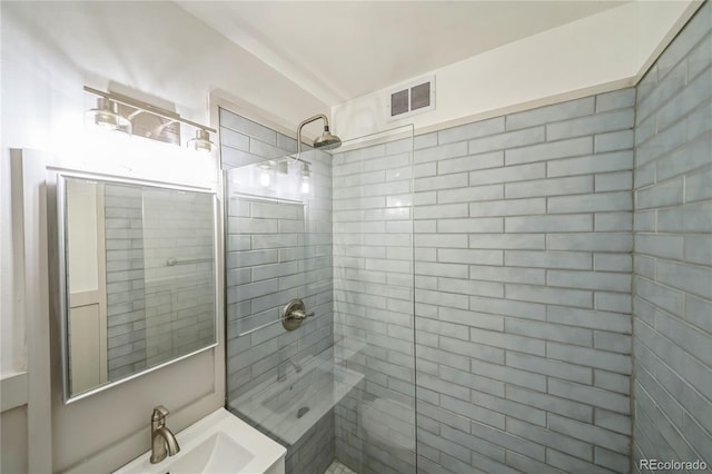 bathroom with a sink, visible vents, and tiled shower