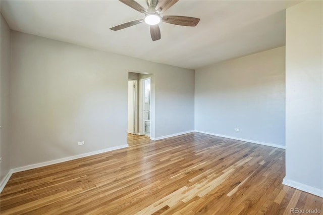 spare room featuring light wood-style flooring, a ceiling fan, and baseboards