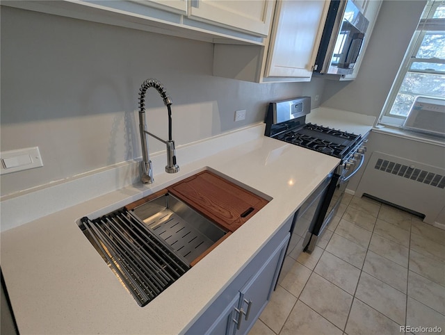 kitchen with light countertops, radiator, appliances with stainless steel finishes, and a sink