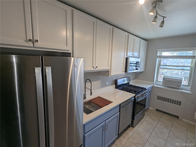 kitchen featuring a sink, white cabinetry, radiator, appliances with stainless steel finishes, and light countertops