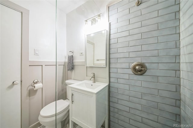 bathroom with vanity, toilet, and a wainscoted wall