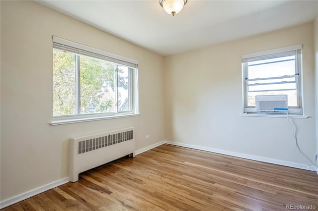 unfurnished room featuring light wood-style flooring, radiator, and baseboards