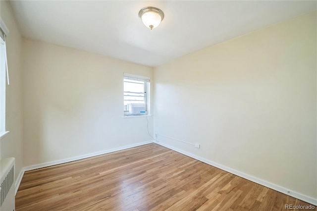 unfurnished room with cooling unit, wood finished floors, and baseboards