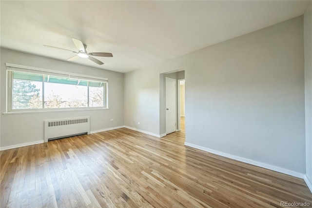 unfurnished room with light wood-style floors, baseboards, radiator, and a ceiling fan