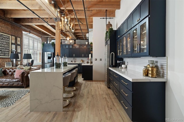 kitchen featuring brick wall, blue cabinetry, and light hardwood / wood-style flooring