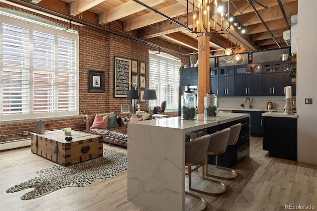 interior space featuring hanging light fixtures, beam ceiling, brick wall, and hardwood / wood-style floors