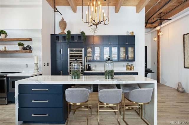 bar featuring blue cabinets, beamed ceiling, decorative light fixtures, and light wood-type flooring