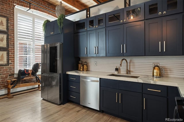 kitchen with beamed ceiling, appliances with stainless steel finishes, sink, and brick wall