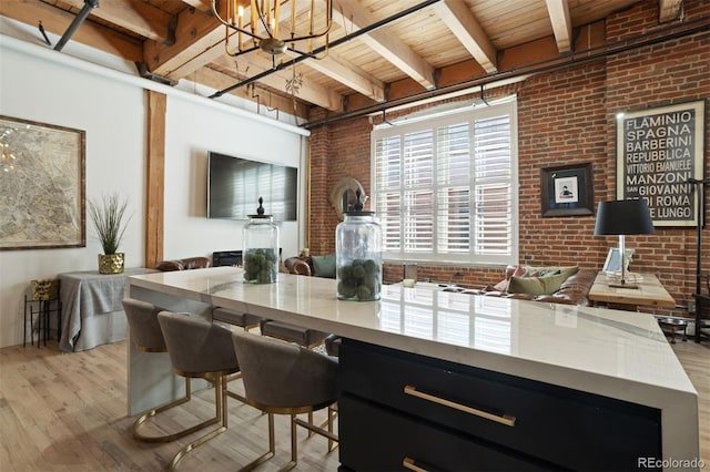 interior space featuring light hardwood / wood-style floors, hanging light fixtures, wooden ceiling, beam ceiling, and brick wall