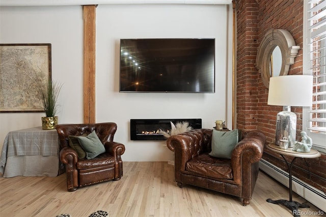 living area with a baseboard heating unit and light hardwood / wood-style flooring