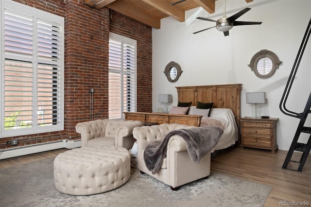 bedroom featuring beamed ceiling, wood-type flooring, ceiling fan, and brick wall