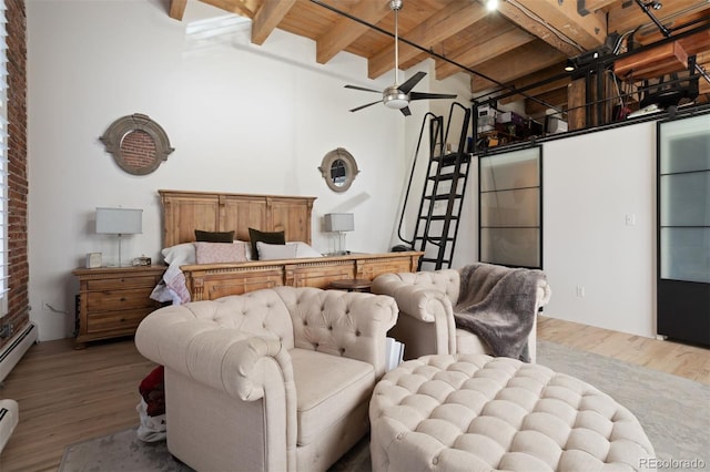 bedroom with wood-type flooring, wooden ceiling, baseboard heating, beam ceiling, and a high ceiling