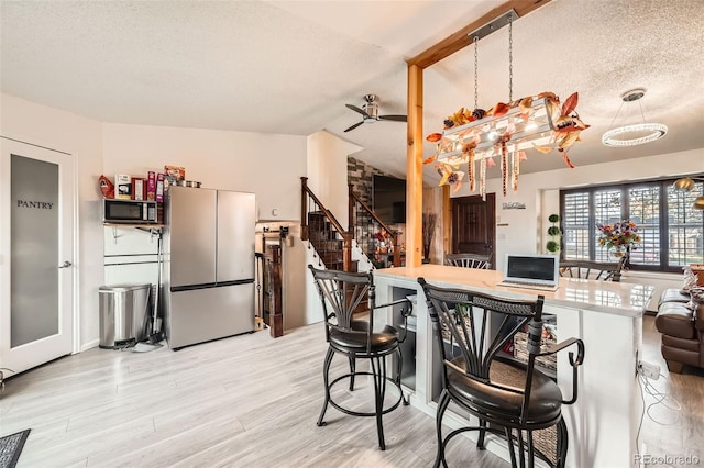 kitchen with appliances with stainless steel finishes, a textured ceiling, light hardwood / wood-style flooring, and ceiling fan