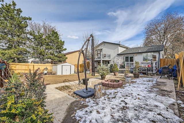 back of house with a wooden deck, a fire pit, and a storage shed