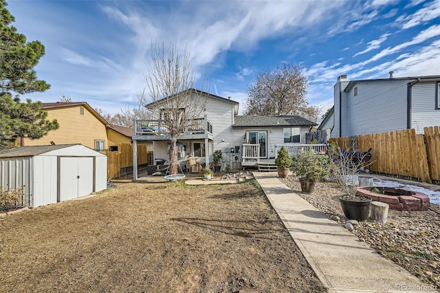 rear view of property featuring a storage shed, a deck, an outdoor fire pit, and a balcony