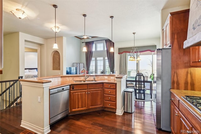 kitchen featuring stainless steel appliances, a sink, dark wood-type flooring, and brown cabinets
