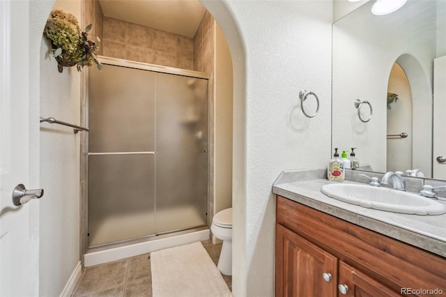 full bath with toilet, a stall shower, vanity, and tile patterned flooring