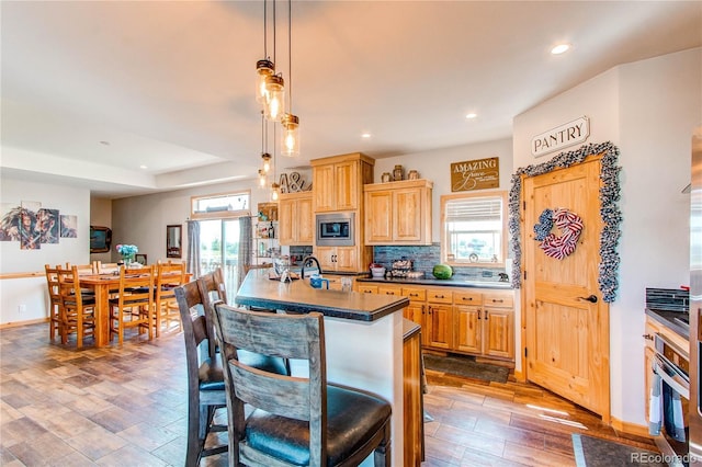 42919 Vista Rdg, Parker, CO 80138 - kitchen with appliances with stainless steel finishes, wood finished floors, light brown cabinets, recessed lighting, and a kitchen bar