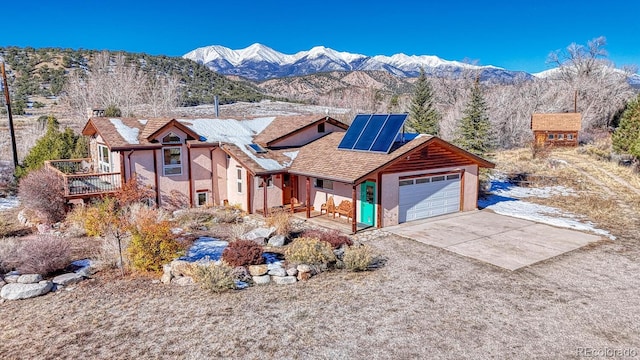 view of front of home with solar panels, a garage, and a mountain view