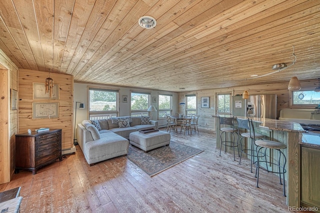 living room featuring baseboard heating, wooden walls, wood ceiling, and wood-type flooring