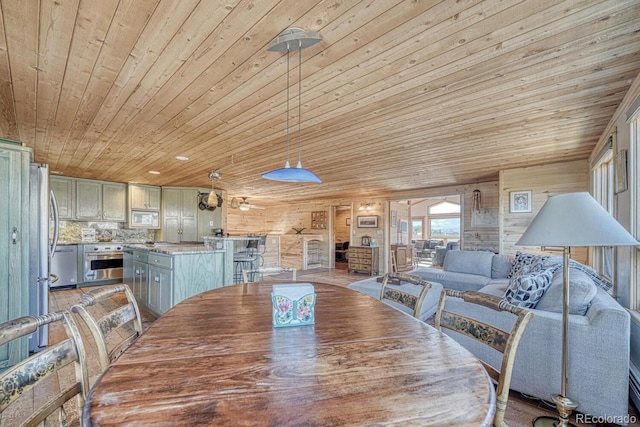 dining area with ceiling fan, wood walls, and wood ceiling