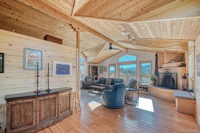 living room featuring lofted ceiling with beams, light hardwood / wood-style floors, wooden walls, and wood ceiling