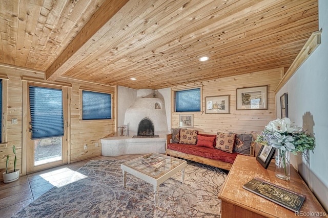 living room featuring beam ceiling, a large fireplace, wooden walls, and wood ceiling