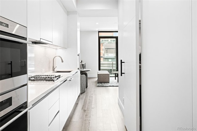 kitchen with white cabinets, modern cabinets, stainless steel appliances, light countertops, and a sink