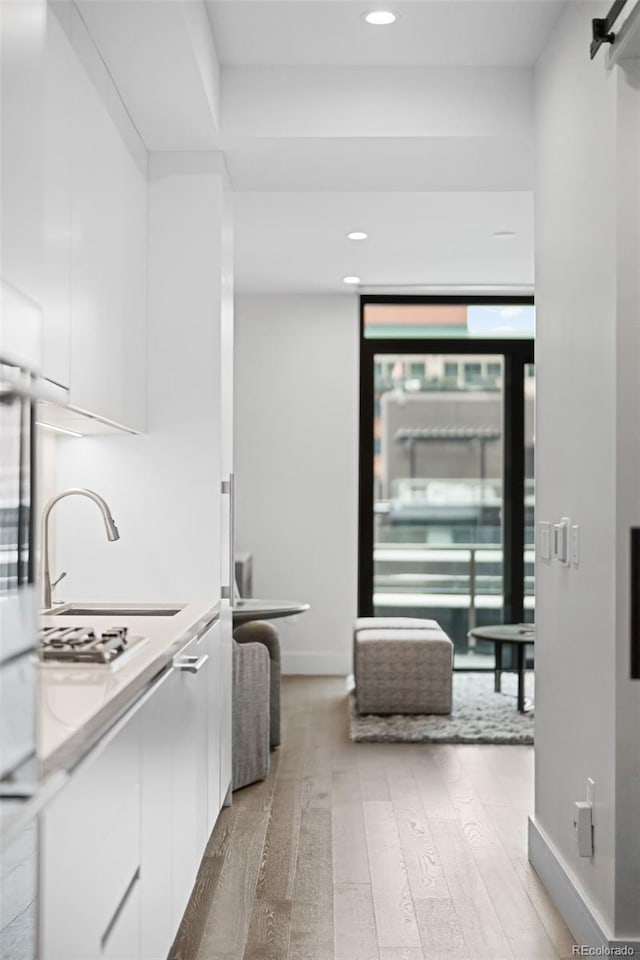 kitchen featuring light wood finished floors, a barn door, white cabinetry, and baseboards