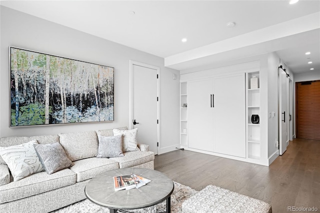 living area with recessed lighting, wood finished floors, baseboards, and a barn door