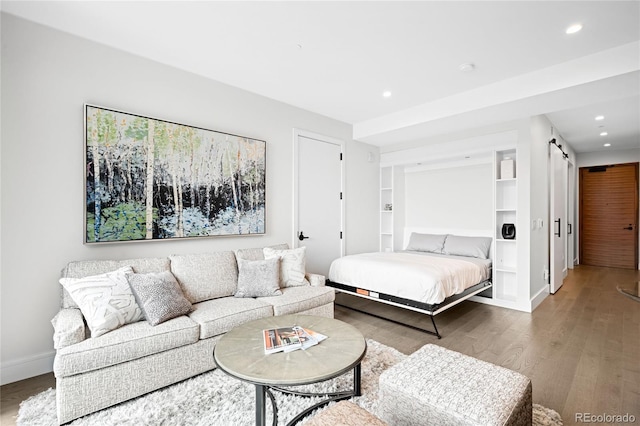 bedroom featuring baseboards, a barn door, wood finished floors, and recessed lighting