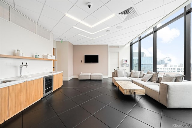 living area with baseboards, wine cooler, visible vents, and a drop ceiling