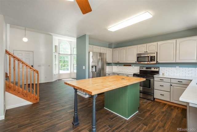 20445 Mitchell Pl, Denver, CO 80249 - kitchen with stainless steel appliances, butcher block countertops, decorative backsplash, dark wood-style floors, and a breakfast bar