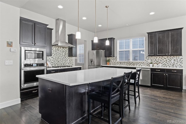 1867 W 137th Ln, Broomfield, CO 80023 - kitchen with stainless steel appliances, wall chimney exhaust hood, a kitchen island, dark wood finished floors, and backsplash