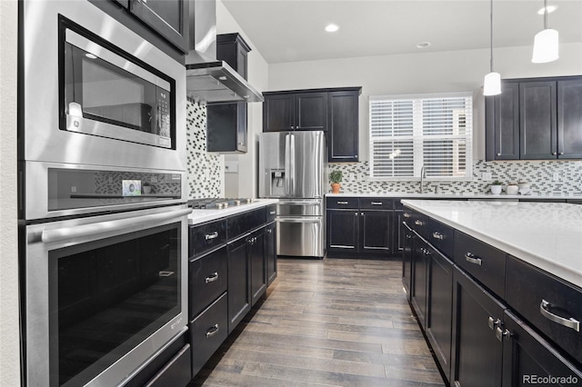 1867 W 137th Ln, Broomfield, CO 80023 - kitchen featuring stainless steel appliances, wall chimney range hood, dark wood-type flooring, dark cabinetry, and recessed lighting
